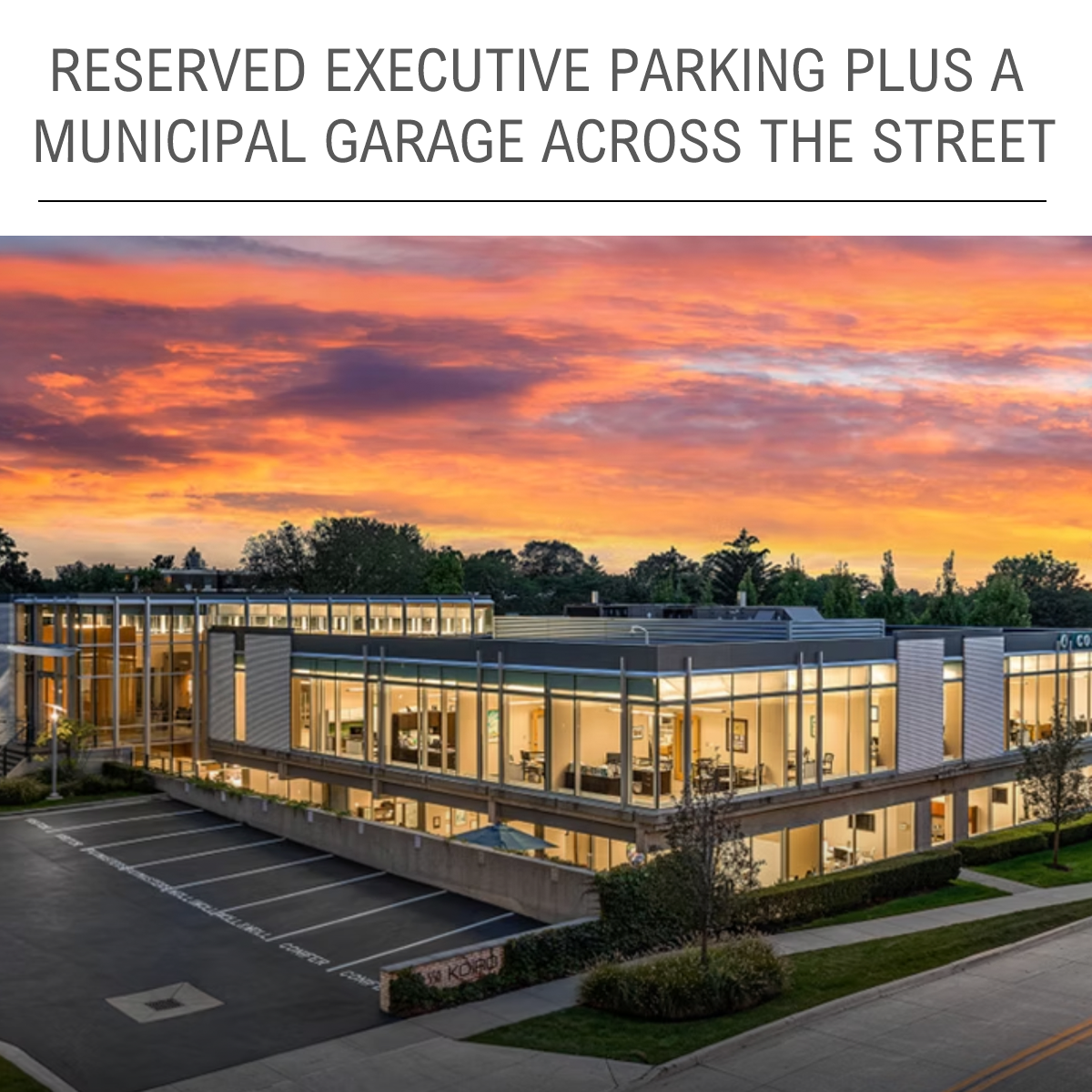 Exterior view of modern office building featuring reserved parking and curb appeal at sunset
