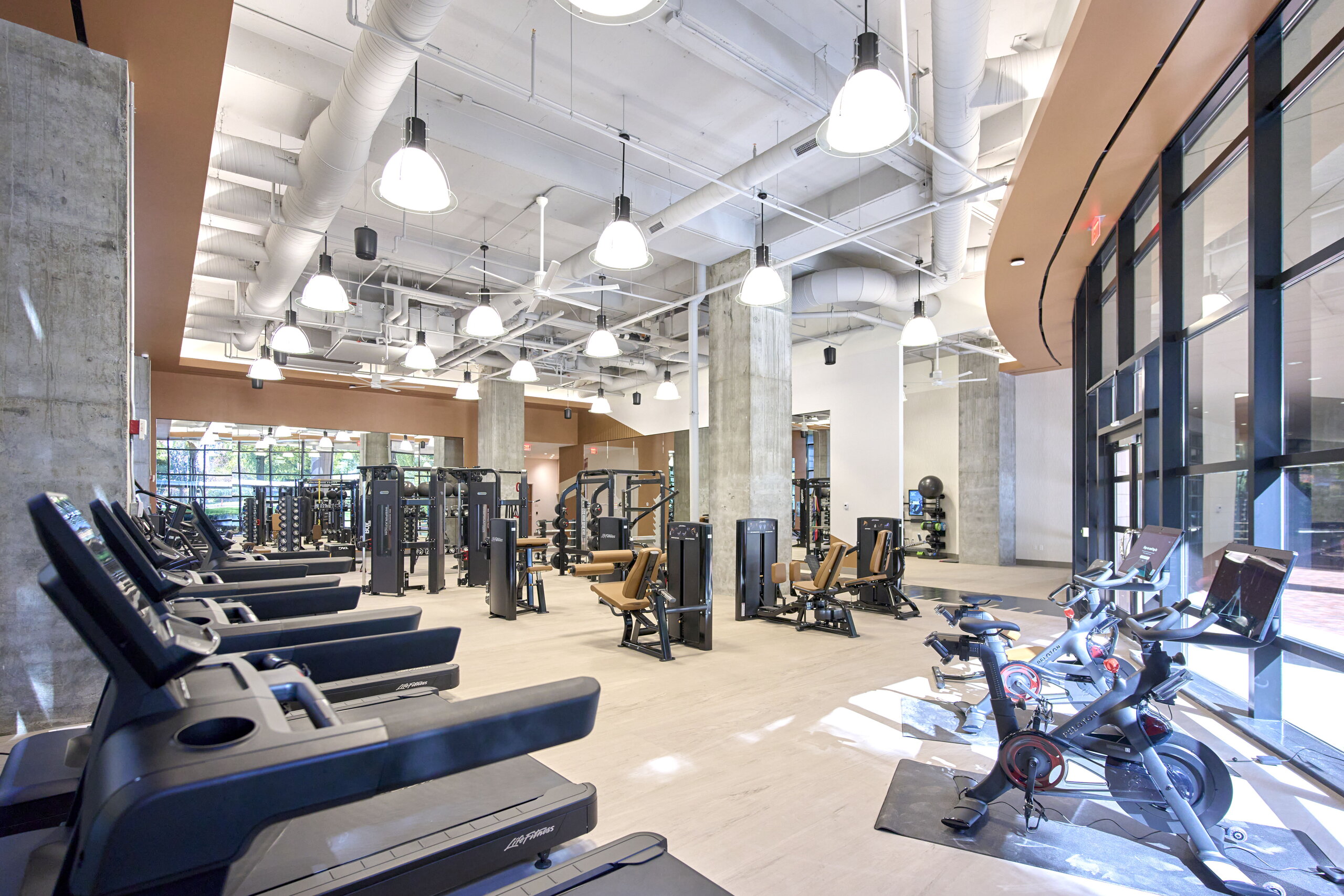 Modern fitness center with exercise machines and windows